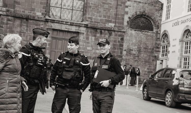 Photo prise lors d'une maraude. 2 gendarmes et un policier entrain de discuter avec une personne agée. Ils sourient.