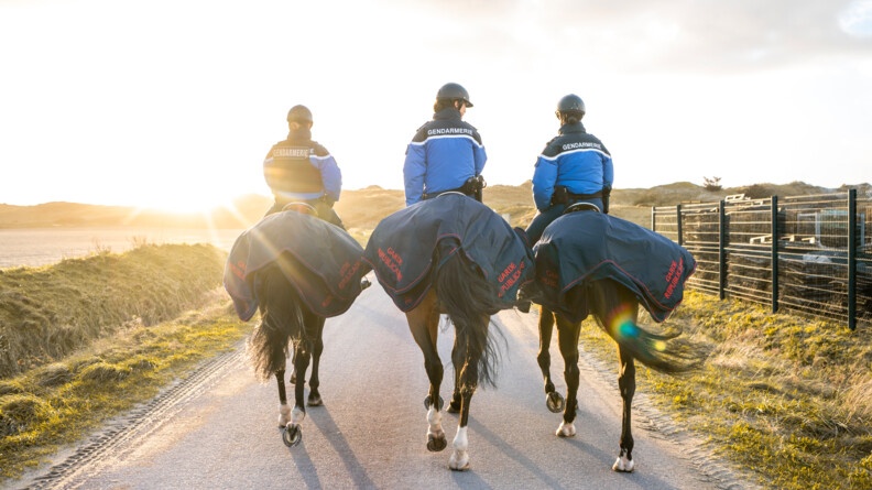 Gardes républicaines s'éloignant avec leurs chevaux en destination du soleil couchant.