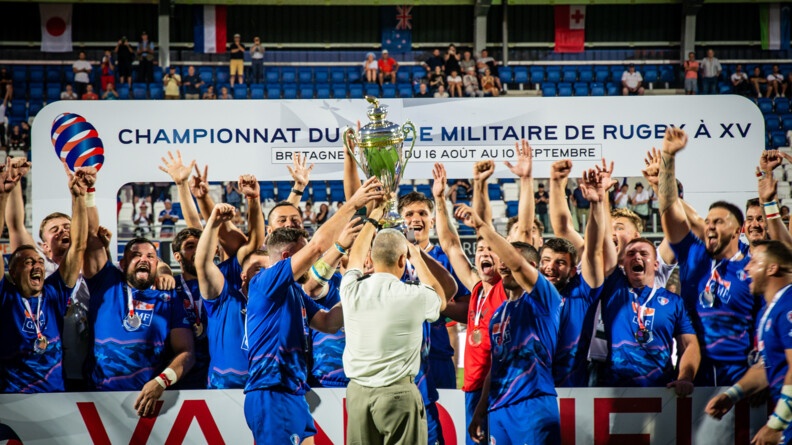 Les Français champions du Monde de rugby militaire brandissent la coupe devant les supporters.