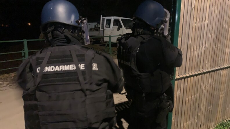 Deux gendarmes mobiles de dos prêt à passer derrière un mur