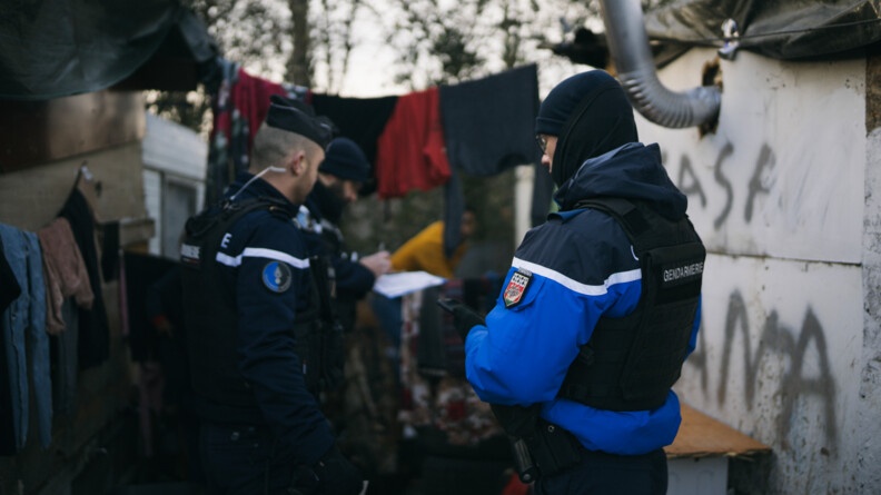 Trois gendarmes qui contrôlent et interpellent des gens dans une décharge publique.