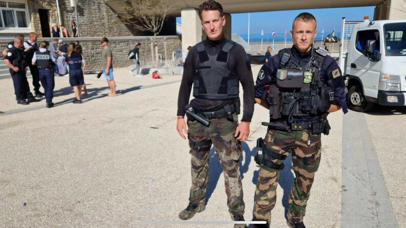 Portrait en pied des deux gendarmes de la BGE dédiée à la LIC. Derrière eux, un groupe de policiers.