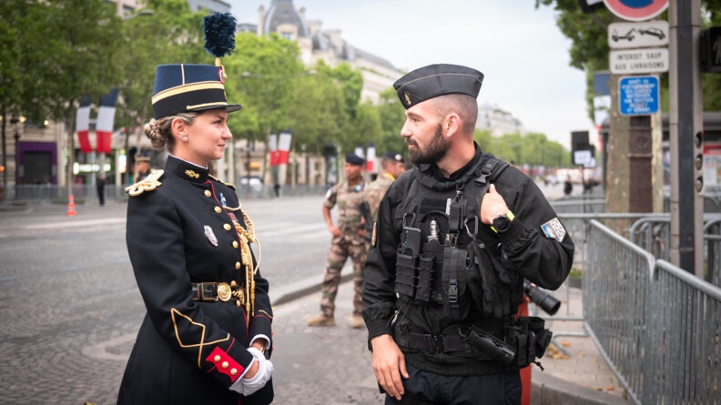 Une élève-officier de l'EOGN, à gauche, de profil, échange avec un camarade gendarme mobile sur les Champs-Elysées