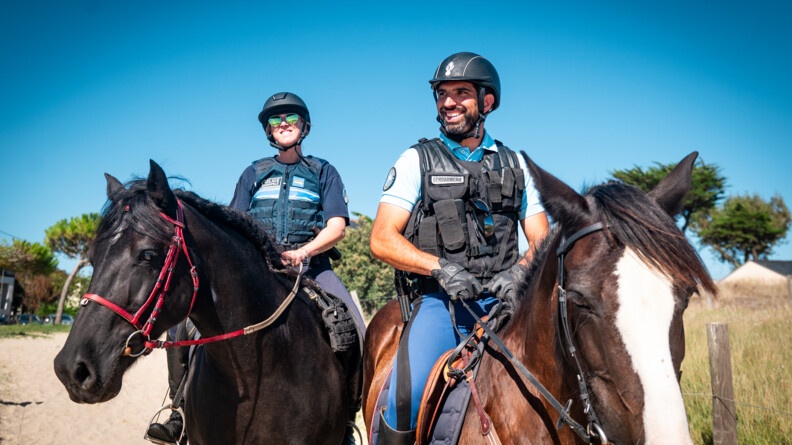 Un gendarme et une policière municipale surveillent une plage à cheval.