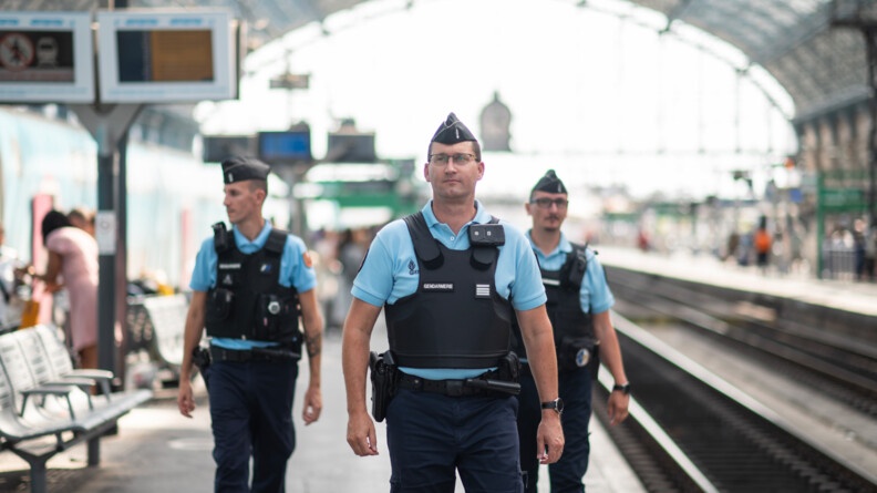 Le CEN Arthur Moulin suivi deux gendarmes vus de face, avancent sur un des quais de la gare de Bordeaux-Saint-Jean.