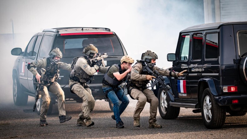 Quatre hommes du GIGN, fusil à la main, s'approchant d'un véhicule tout terrain de couleur noir
