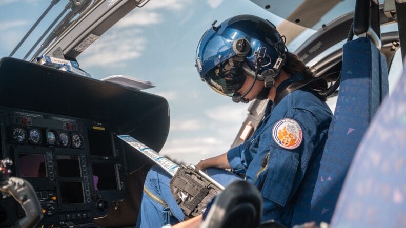 Une pilote des forces aériennes gendarmerie dans le cockpit, casquée, en train de faire la check-list