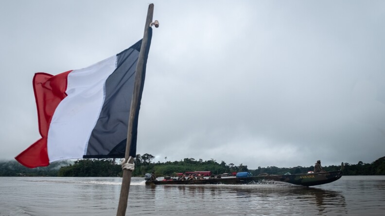 Drapeau français devant une pirogue sur une rivière en Guyane