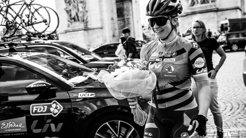 La garde Derbesse tenant un bouquet de fleurs après une compétition de vélo.