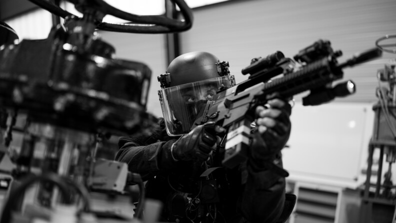 Photo en noir et blanc d'un militaire du PSPG armé.