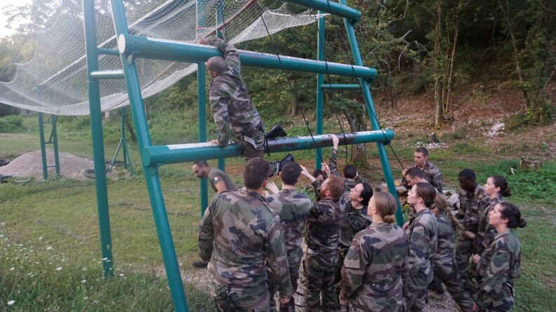 En extérieur, une dizaine de jeunes de la CPT attendent leur tour pour passer sur un obstacle aérien avec un filet.