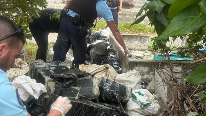 Photo de jour montrant quatre gendarmes entrain de déplacer des sacs noirs et blancs.