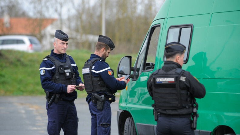 Trois gendarmes contrôlent une camionette de couleur verte.