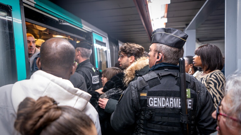 Gendarmes régulant les personnes à l'entrée d'une rame de métro pour permettre à la porte de se fermer (bis).