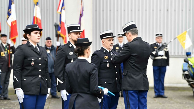 Un officier de dos décore un sous-officier en vareuse à côté duquel se trouvent deux autres décorés.