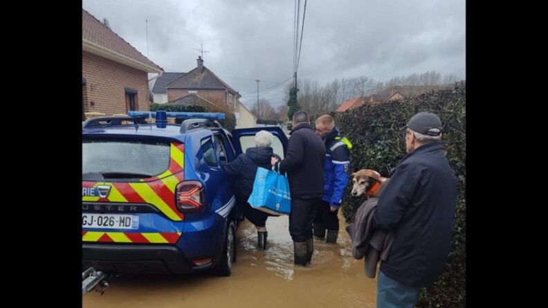 Un militaire aide une vieille dame à monter dans le véhicule de la gendarmerie pour évacuer une zone inondée. A ses cotés, se trouve deux autres habitants.