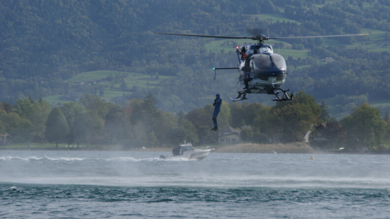 Le gendarme plongeur saute dans le lac depuis l'hélicoptère.