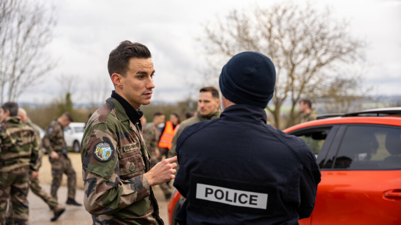 Un gendarme runner, à gauche de face, échange avec un policier (de dos)