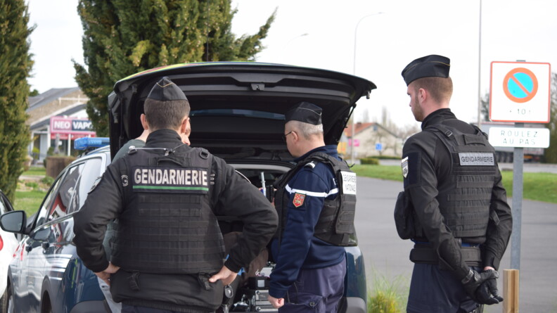 Trois gendarmes fouillent le coffer d'un véhicule