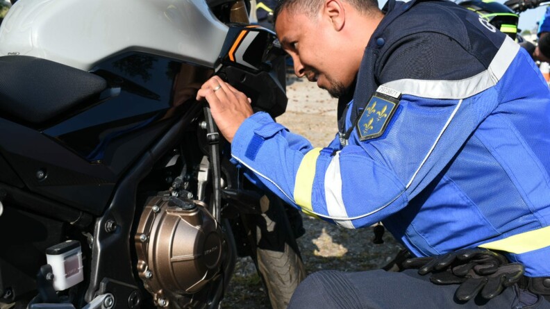 Un motocycliste de l'EDSR 78 de profil, agenouillé à côté d'une moto, dont il contrôle les équipements.