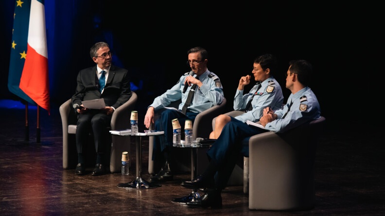 M. François Cazals, animateur de la table ronde, aux côtés de trois officiers de gendarmerie, deux hommes et une femme (au centre), assis sur une scène.