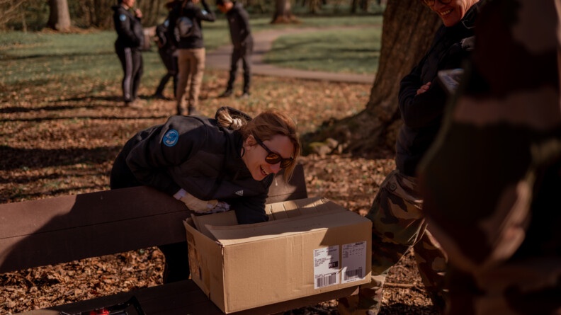 Claire, participante au stage Cent'Or, plonge sa main dans un carton pour tenter de deviner un objet lié à l'équitation, lors de la séance ORFA (Optimisation des ressources des forces armées) en forêt de Saint-Germain-en-Laye.