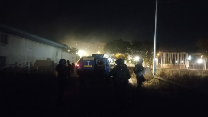 Des gendarmes mobiles progressent en pleine nuit aux côtés d'un véhicule blindé.
