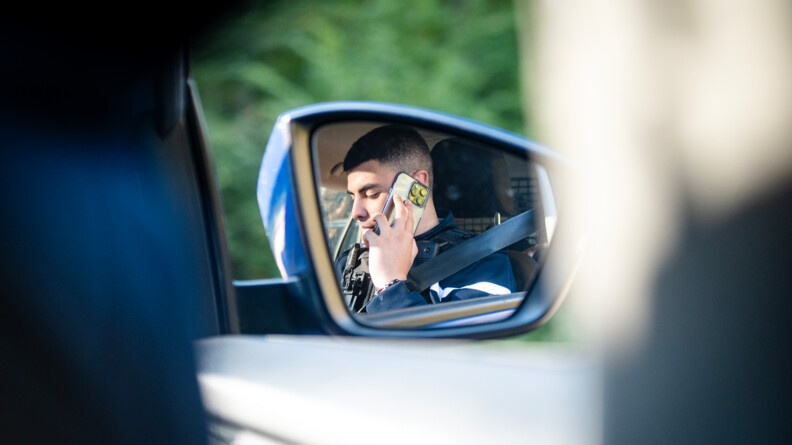 L'image d'un gendarme au téléphone au volant de son véhicule se reflète dans son rétroviseur