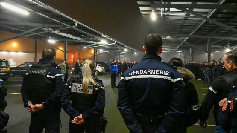Il fait nuit, un groupe de gendarmes sont réunis dans un parking. Un gendarme est au centre et fait un discours.