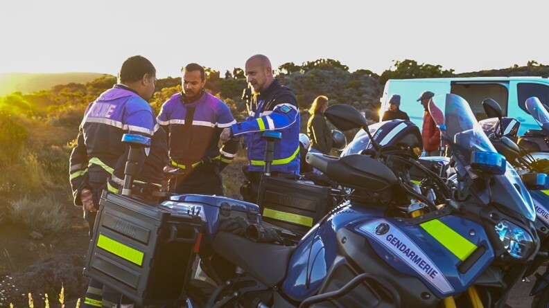 Des gendarmes échangent entre eux devant leur moto.