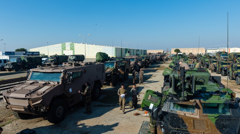 Des véhicules de différents types, blindés, alignés d'avant en arrière de l'image, avec des militaires faisant des vérifications