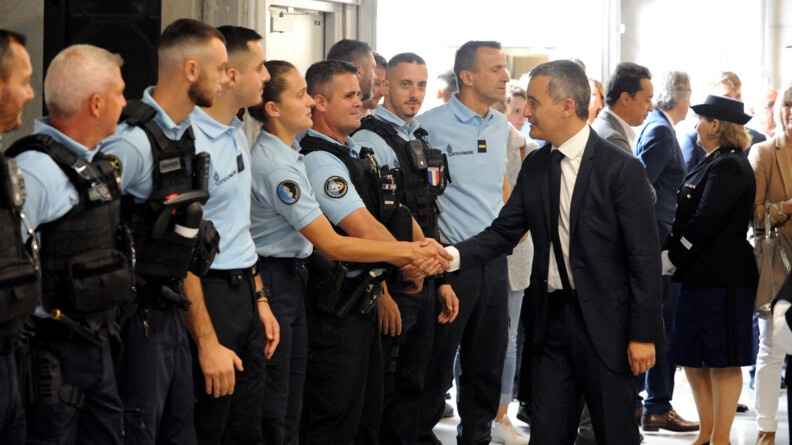 Plusieurs gendarmes en tenue d'intervention sont alignés, tandis que le ministre de l'Intérieurvient leur serrer la main.
