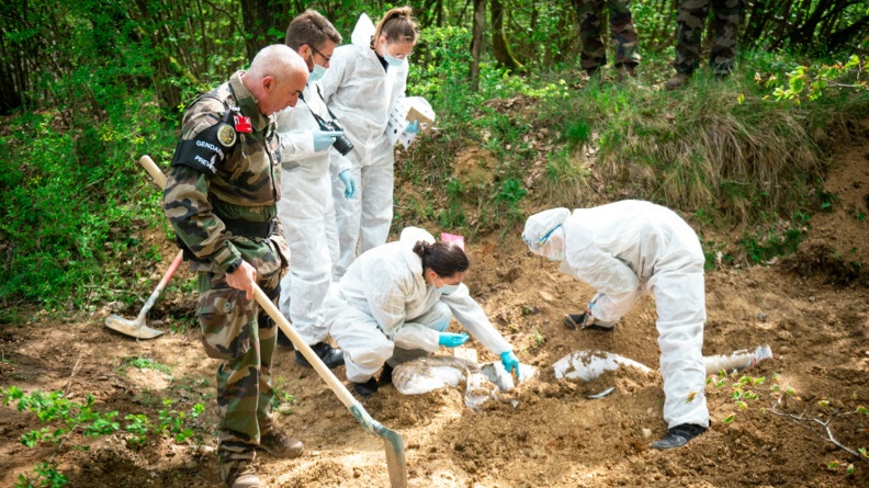 4 gendarmes en combinaison blanche et un gendarme en treillis exhument du charnier un corps.