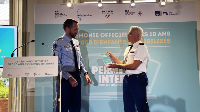 Le général Jean-Valéry Lettermann, chef du SIRPA gendarmerie, à droite, remet un trophée de l'engagement à l'adjudant-chef Christophe, à gauche, à côté du pupitre.