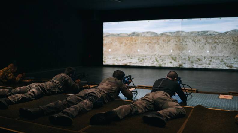 Quatre gendarmes et militaires en treillis allongés sur le sol avec leur FAMAS; exercice de tir vers un écran au mur