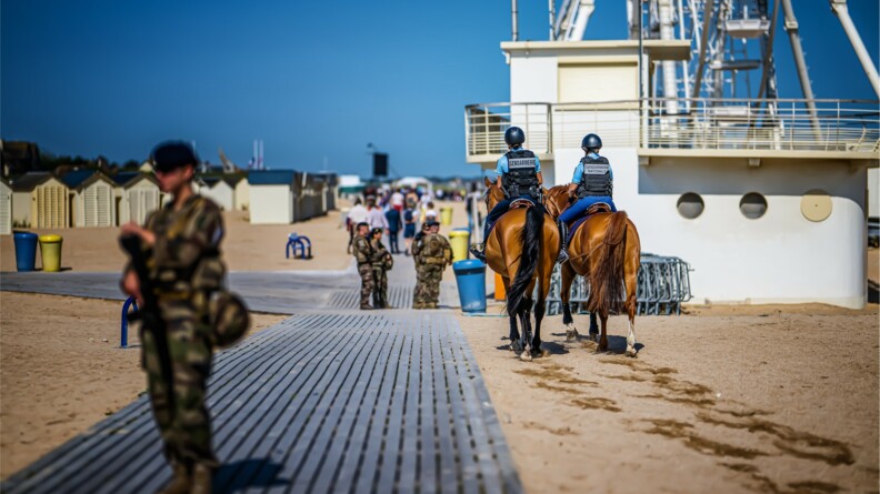 Deux gendarmes à cheval et des militaires sécurisent la cérémonie sur la plage.