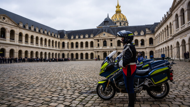Vue de profil d'un motocycliste de la gendarmerie, vue sur les Invalides