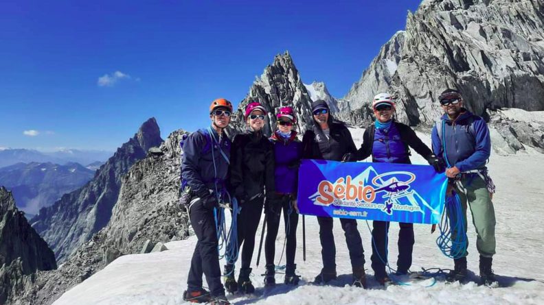 Des membres de l'association Sébio posent pour une photo en haut d'un sommet avec la banière de l'association.