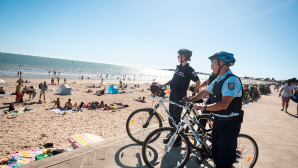 Un gendarme et une policière municipale surveillent une plage.
