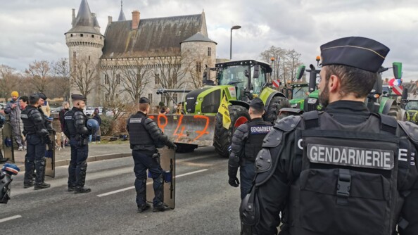 Devant un petit chateau, des gendarmes mobiles font face aux tracteurs.