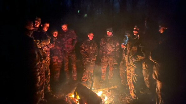 Photo de 11 gendarmes dans la nuit, entrain de discuter debout autour d'un feu de camp.