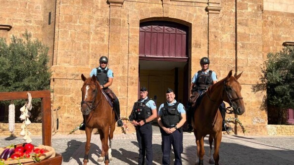 Devant une église et à cheval, deux gendarmes accompagnés de deux autres gendarmes à pied, assurent la sécurisation de la messe de l'assomption.