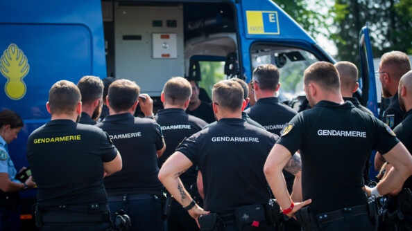 Groupe de gendarmes de dos devant un des nouveaux véhicules de commandement et de transmission de la gendarmerie.