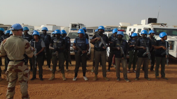 Un gendarme au premier plan à gauche briefe des forces de sécurité qui portent armes et casques.