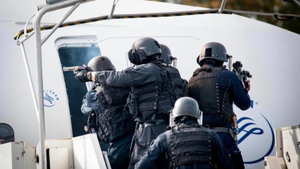 Des membres du GIGN apparaissant de dos, armés, donnant l'assaut à la porte d'un avion