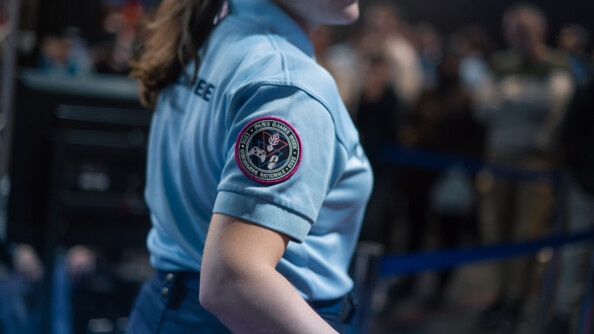 On voit de biais une femme gendarme en tenue en train d'avancer. Sur le manche droite de son polo bleu clair est visible l'écusson de la gendarmerie nationale à l'éffigie de la Paris Games Week