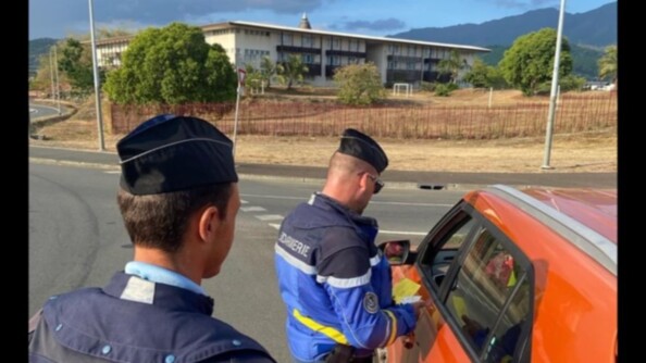 En Nouvelle-Calédonie, deux gendarmes contrôlent un véhicule juste avant les fêtes du nouvel an. Il fait jour et le véhicule est orange.