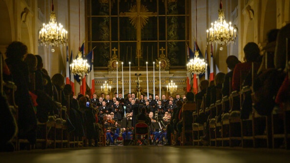 Vue centrale de la cathédrale Saint-Louis avec au milieu, de dos, le chef d'orchestre et de face le choeur de l'armée française. Sur chaque coté, le public, captivé, regarde le concert.