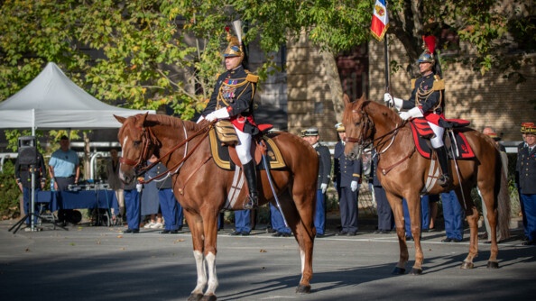 De trois quart avant gauche, deux cavaliers de la Garde républicaine sur leurs chevaux. Le premier est général et le second porte-fanion. Derrière eux en arrière-plan, alignés, des officiers de différentes armées
