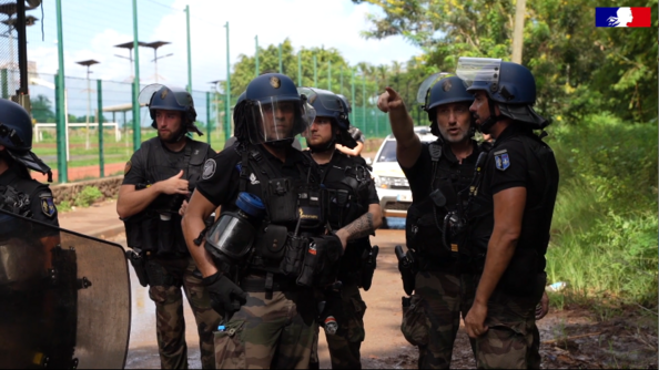 Six gendarmes mobiles casqués, vêtus de tee-shirts noirs et de pantalons de treillis kaki, en mission de sécurisation à Mayotte.